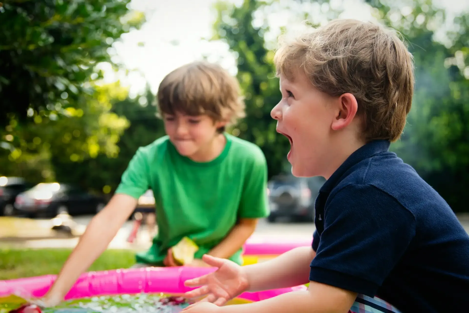 Boy in blue shirt screaming near boy in green crew neck shirt